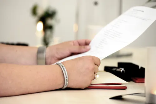 Hände, die ein Blatt Papier halten. 