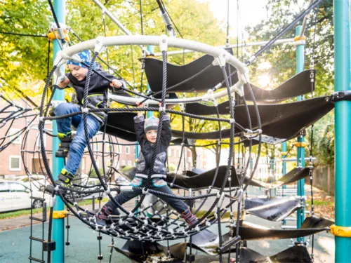 Zwei spielende Kinder auf einem Klettergerüst.