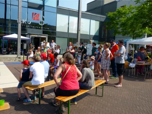 Besucherinnen und Besucher des Sommerfestes schauen sich eine Aufführung an.