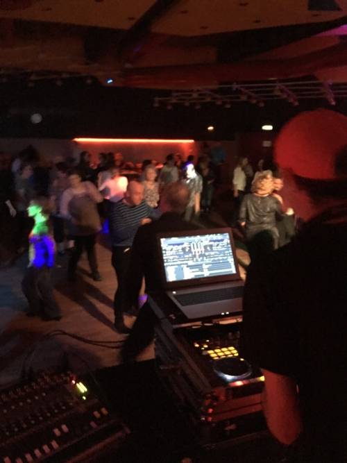 Tanzende Menschen und der Discjockey legt Platten auf.