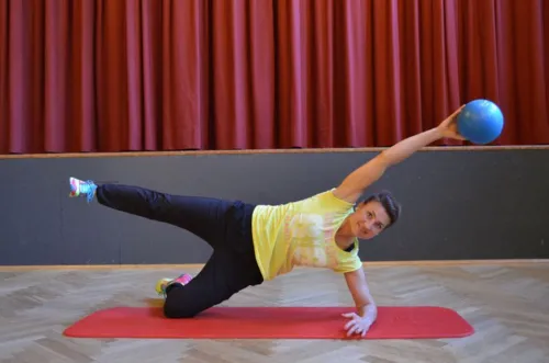 Zu sehen ist eine Frau mit Ball auf Yogamatte