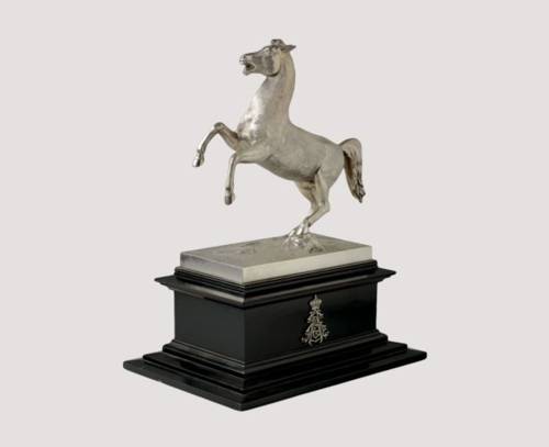 Tischfigur aus Silber von Carl Büsch, 1904: Sachsenross (nach dem Vorbild von A. Wolff, Berlin) auf schwarzem Holzsockel.
An der silbernen Bodenplatte, auf die das Pferd geschraubt ist, seitlich Stempel: BüscH 800, Halbmond und Krone (= Hannoverscher Goldschmied). Am profilierten Sockel an der einen Längsseite die Initialen EA mit Krone (Ernst August Herzog von Cumberland) und auf der anderen eine Inschrifttafel: „Dem Gestütsdirektor Schrenk in Herrenhausen/in dankbarer Anerkennung treuer Dienste/1856 bis 1904 gewidmet/Ernst August/Herzog von Cumberland, Herzog zu Braunschweig und Lüneburg“.