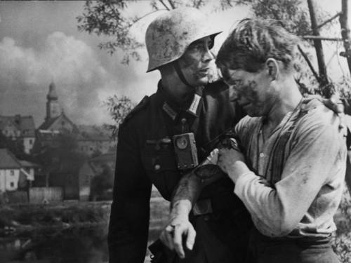 Im Bild zu sehen sind in schwarz-weiß zwei junge Soldaten. Einer scheint verletzt.