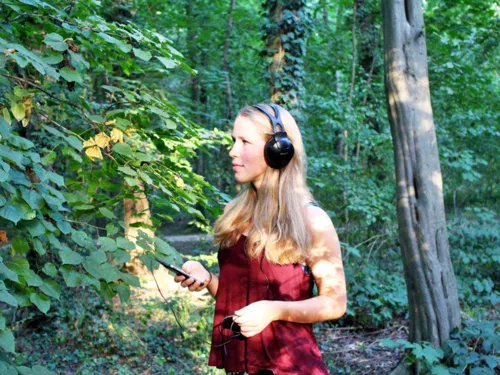 Junge Frau mit Kopfh&ouml;rern im Wald