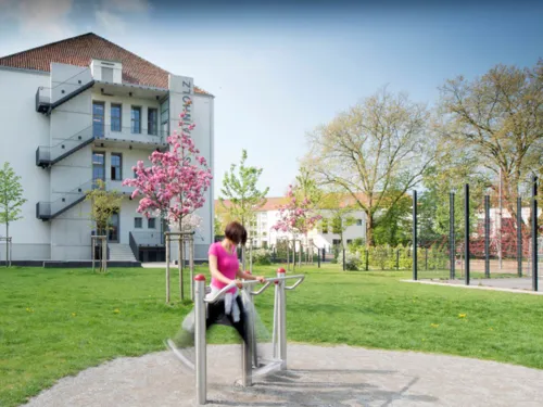 Eine Frau trainiert an einem Fitnessgerät vor blühenden Bäumen