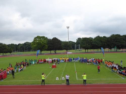 Spielfeld in einer Sportarena. Darauf und drumherum stehen Menschen. 
