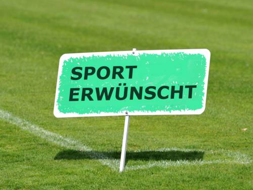 Rasenfläche, auf der ein Schild steht, auf dem "Sport erwünscht" zu lesen ist.  