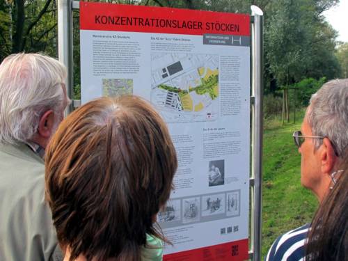 Teilnehmer einer Fahrradtour betrachten die Informationstafel zum KZ Stöcken, 2014.