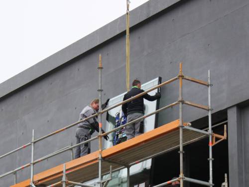 Zwei Arbeiter platzieren ein Fensterglas an der Westloggia des Erweiterungsbaus des Sprengel Museums