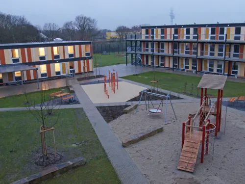 Ein Hof, gesäumt von Gebäuden. Darauf ein Spielplatz. 