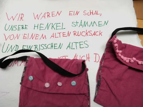 Zwei Taschen auf einem St&uuml;ck Tapete. Auf der steht: Wir waren ein Schal, unsere Henkel stammen von einem alten Rucksack und ein bisschen Altes...