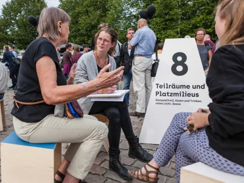 Menschen im Gespräch auf einem Platz. 