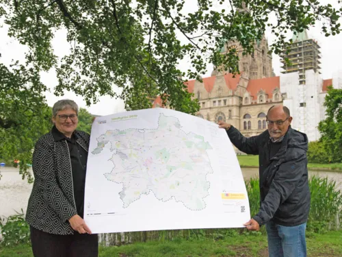 Eine Frau und ein Mann mit einem Plakat in einem Park. 
