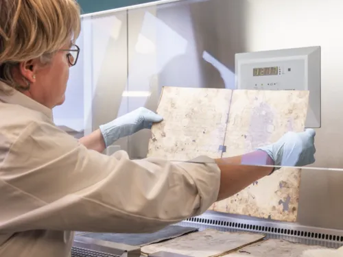 Eine Frau hält ein Archivstück in den Händen