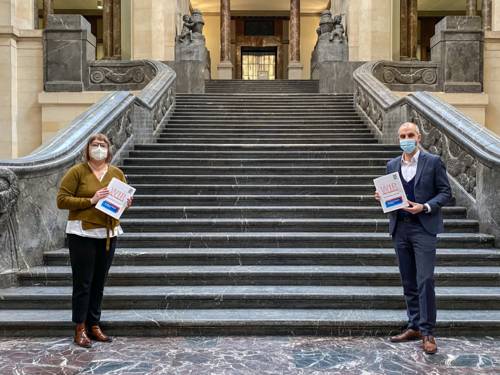 Sozialdezernentin Sylvia Bruns und Oberbürgermeister Belit Onay vor der Treppe im Neuen Rathaus. Sie tragen einen Mund-Nasen-Schutz, halten Abstand und in ihren Händen das Dokument "Wir sind Hannover". 