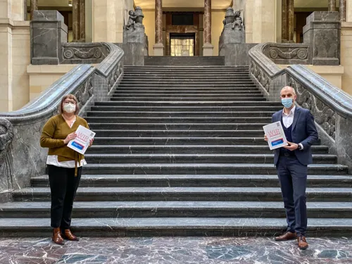 Sozialdezernentin Sylvia Bruns und Oberbürgermeister Belit Onay vor der Treppe im Neuen Rathaus. Sie tragen einen Mund-Nasen-Schutz, halten Abstand und in ihren Händen das Dokument "Wir sind Hannover".