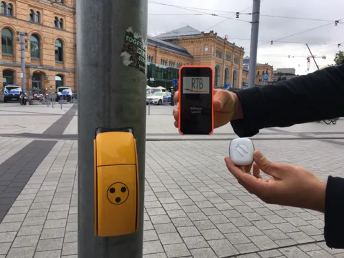 Sender mit Druck-Knopf und ein Smartphone mit LOC.id-App