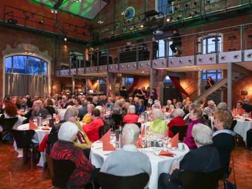 Im Restaurant Cavallo, der umgebauten königlichen Reithalle in der Dragonerstraße, sitzen an vielen Tischen festlich gekleidete ältere Menschen und genießen bei Essen und Trinken ein Showprogramm.