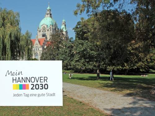 Bilck auf das Rathaus. Im Vordergund das Logo vom Stadtdialog "Mein Hannover 2030"