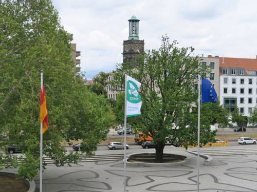 Auf dem Rathausvorplatz weht zwischen der Deutschlandflagge und der Europaflagge die Flagge der Bürgermeister für den Frieden mit einer weißen Friedenstaube