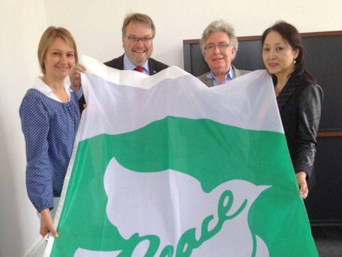 Evelyn Kamissek, Thomas Hermann, Michel Cibot und Miho Cibot mit der Flagge von Mayors for Peace 