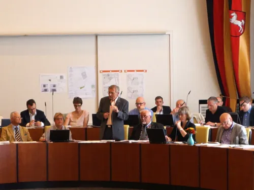Mitglieder des Rates hören einem Redner im Sitzungssaal zu