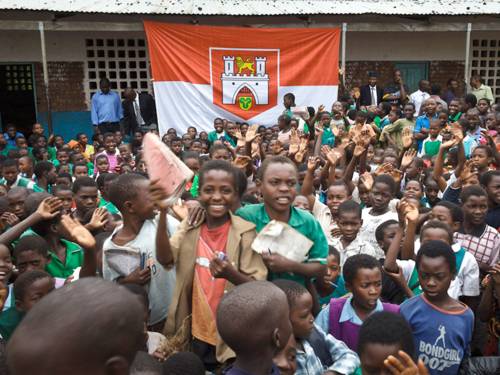 Kinder und Jugendliche in Blantyre haben sich in einem Hof versammelt; im  Hintergrund die Fahne mit dem Wappen Hannovers