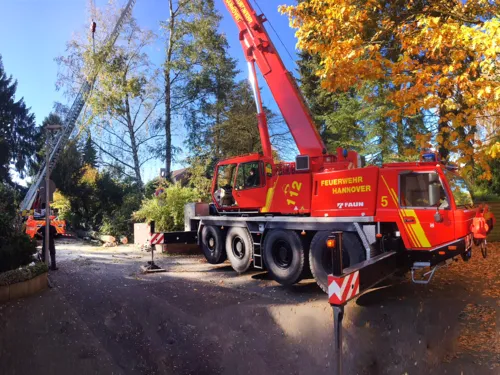 Im Vordergrund ein Kran der Feuerwehr Hannover, im Hintergrund eine Drehleiter mit Einsatzkräften der Feuerwehr Hannover. Die Fahrzeuge stützen den schrägliegenden Baum.