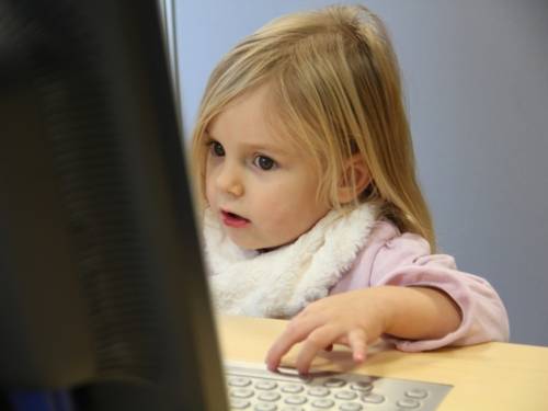 Ein kleines Mädchen sitzt an einem Computer-Arbeitsplatz