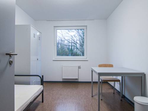 Ein Raum mit einem Bett, einem Stuhl, einem Tisch und einem Schrank