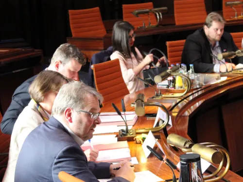 Fünf Personen - zwei Frauen und drei Männer - sitzen im Hodlersaal hinter Pulten.