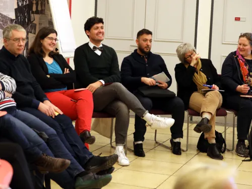 Etwa zehn Personen sitzen im Foyer des Hauses der Jugend auf Stühlen. Ein Mann in der Mitte lacht.