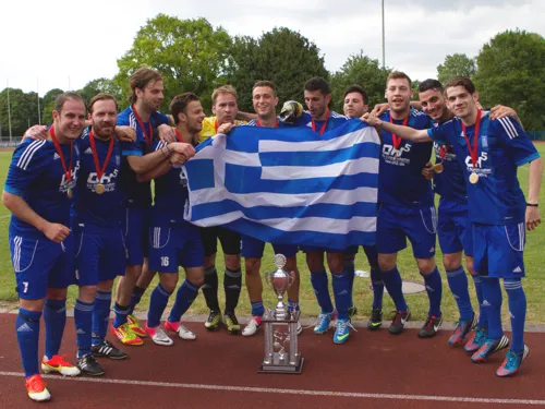 Eine Gruppe junger Männer in blauen Trikos feiert mit Medaillen um den Hals, einer Griechenland-Flagge und einem Silberpokal auf einer Tartanbahn den Sieg beim Internationalen Hannover Cup 2013