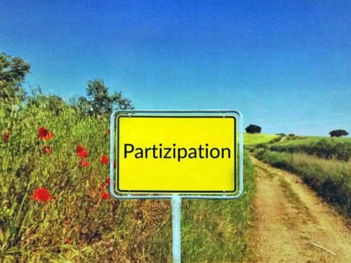 Neben einem Weg steht statt eines Ortsschilds ein Schild mit der Aufschrift "Partizipation".