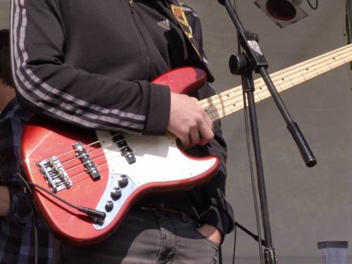 Der Bildausschnitt zeigt einen Jugendlichen, der einen Bass in den Händen hält