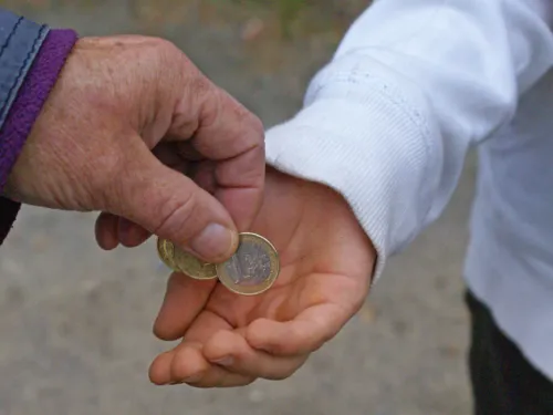 Aus einer &auml;lteren Hand erh&auml;lt eine j&uuml;ngere Hand Geldm&uuml;nzen.