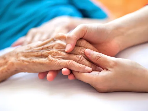 Eine Frau hält die Hand einer älteren Dame
