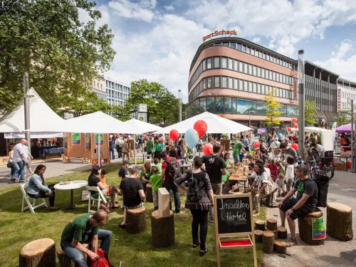 Besucherinnen und Besucher des Autofreien Sonntags kommen an aufgebauten Tischen in der Innenstadt ins Gespräch