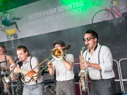 Drei Blechbläser und ein Schlagzeuger auf einer Bühne beim Autofreien Sonntag