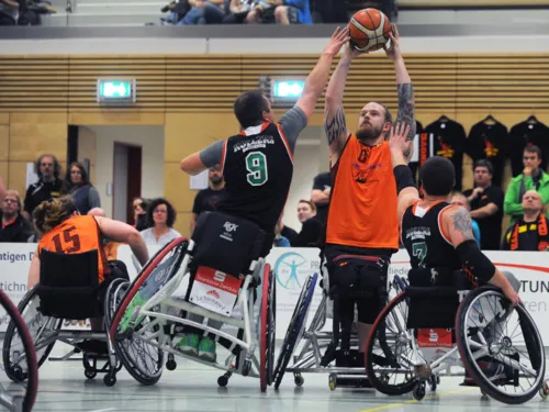Beim Rollstuhlbasketball kämpfen vier Spieler um den Ball.