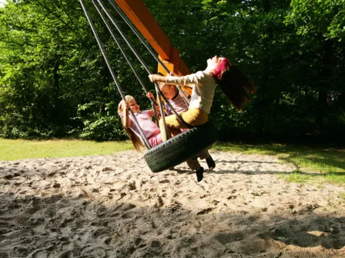 Zwei schaukelnde Kinder auf einem Spielplatz in Mühlenberg