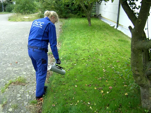 Eine Frau in einem blauen Overall misst mit einem Gerät radiologische Werte.