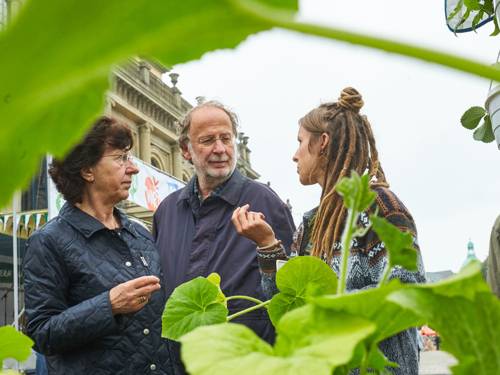 Eine junge Frau spricht mit einem älteren Paar über ökologische Landwirtschaft