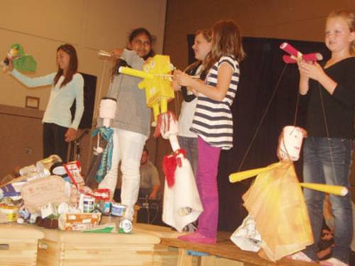Schulkinder zeigen selbstgebastelte Marionetten aus Abfallmaterial