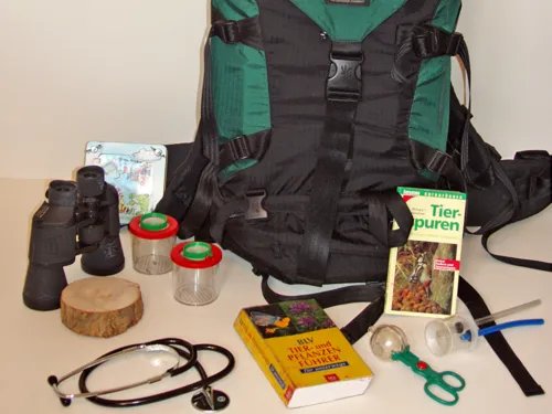 Ein Rucksack mit B&uuml;chern, Stethoskop, Fernglas, Probenbeh&auml;ltern und weiteren Erkundungsutensilien