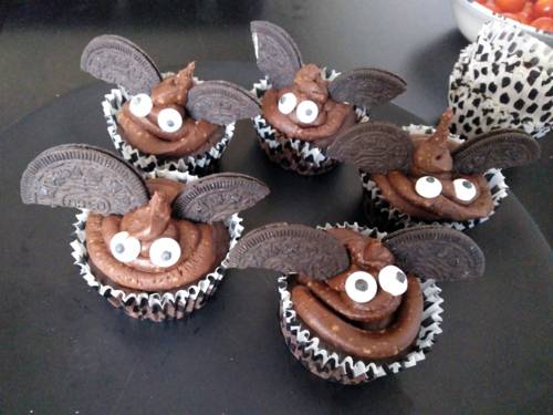 Fünf braune Muffins mit Augen und Flügeln, die an Fledermäuse erinnern.