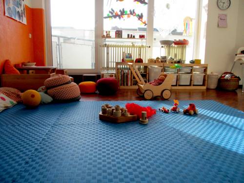 Ein Zimmer mit bunten Spielsachen, im Hintergrund ein großes Fenster.