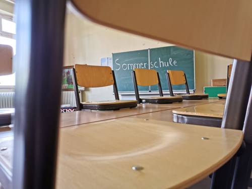 Tafel in leerem Klassenraum mit der Aufschrift "Sommerschule"