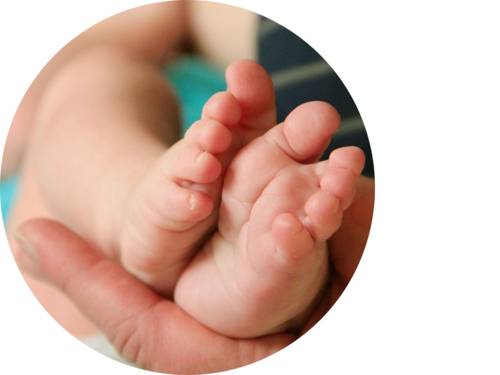 Füße eines Babys in der Hand eines Erwachsenen.