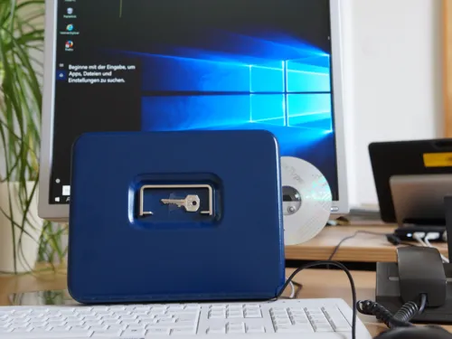 Vor einem Computer steht eine abschließbare Kassette mit einem Schlüssel.